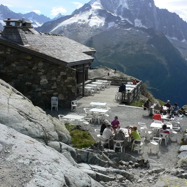 Randonneurs attablés sur la terrasse en pierre du refuge du Lac Blanc, au-dessus de Chamonix, face au massif du Mont-Blanc